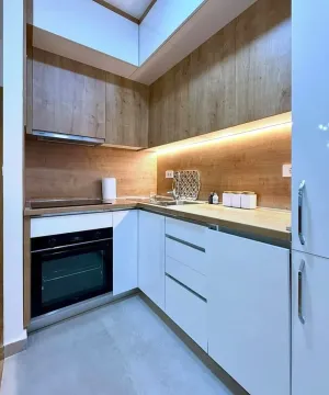 Modern kitchen with white units and wood-grain details. - image 7