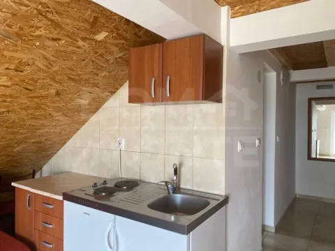Small kitchen with a sink, stove, and wooden cabinetry in the attic. - image 4