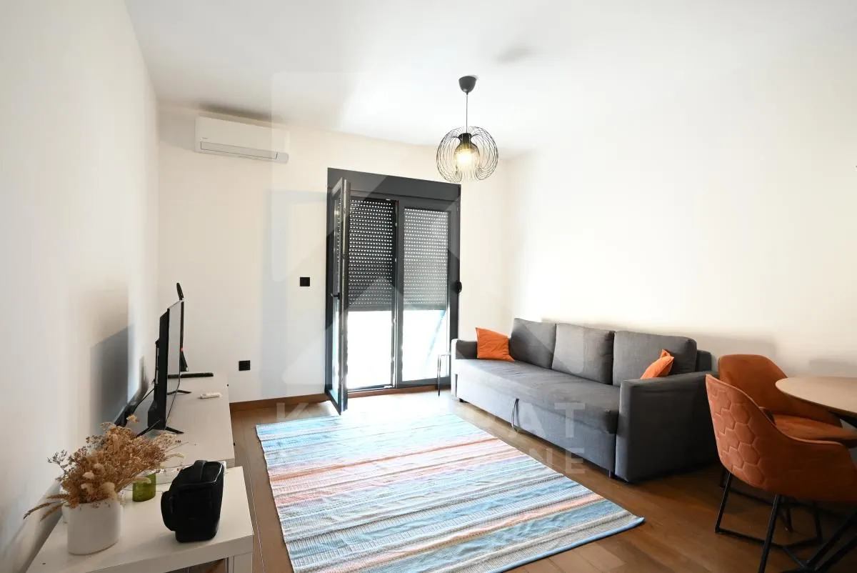Living room with a sofa, dining table, and access to the terrace.