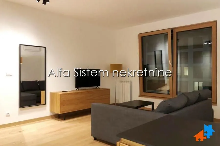 Dnevna soba sa garniturom, TV komodom i velikim prozorom.