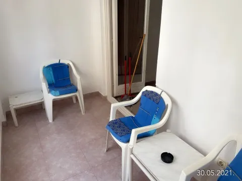 A covered terrace furnished with plastic chairs and a small table. - image 10