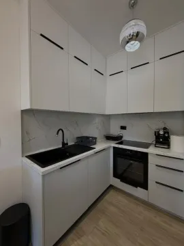 Modern white kitchen with built-in oven and black details. - image 9