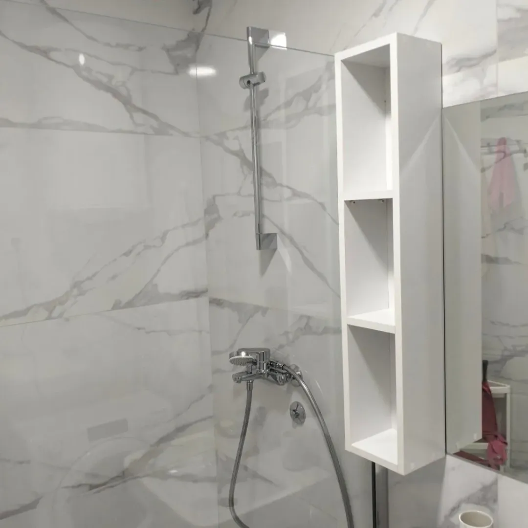 Modern bathroom with a shower cabin and marble tiles.