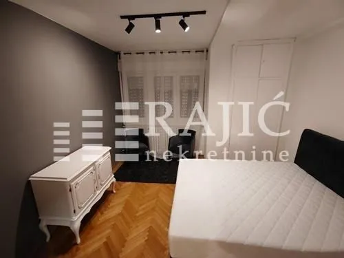 Furnished bedroom with a double bed, white chest of drawers, and wardrobe.