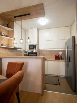 Modern kitchen with white cabinets, wooden accents, and a breakfast bar. - image 8