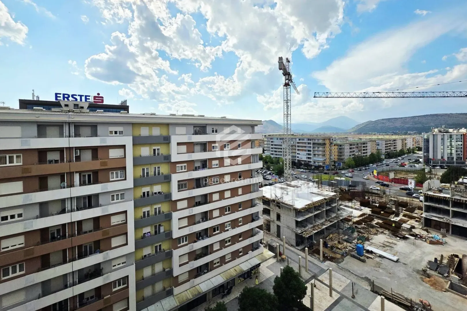 Pogled sa prozora na okolne zgrade i gradilište.