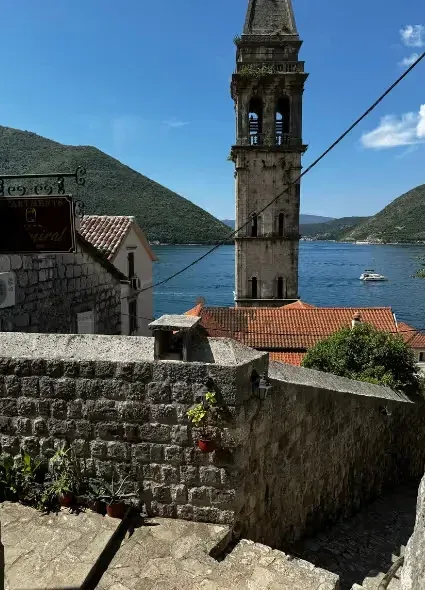 View from the terrace overlooking the old bell tower, sea, and surrounding mountains.