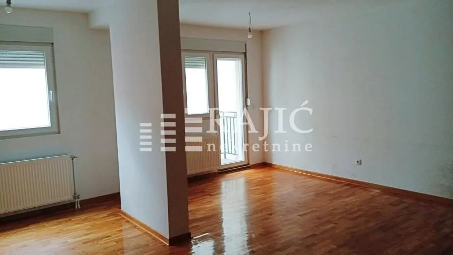 Empty room with hardwood floors and windows.