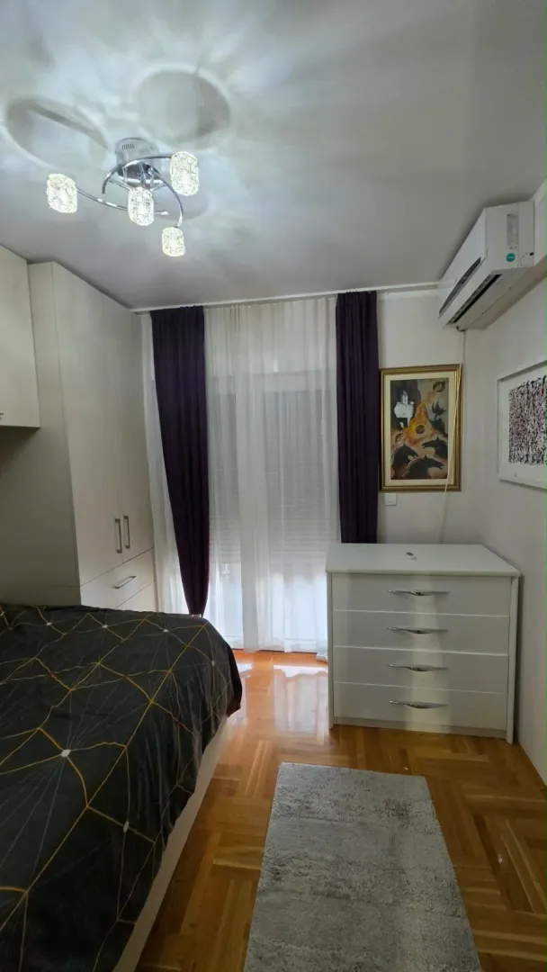 Furnished bedroom with a double bed, wardrobe, and chest of drawers.