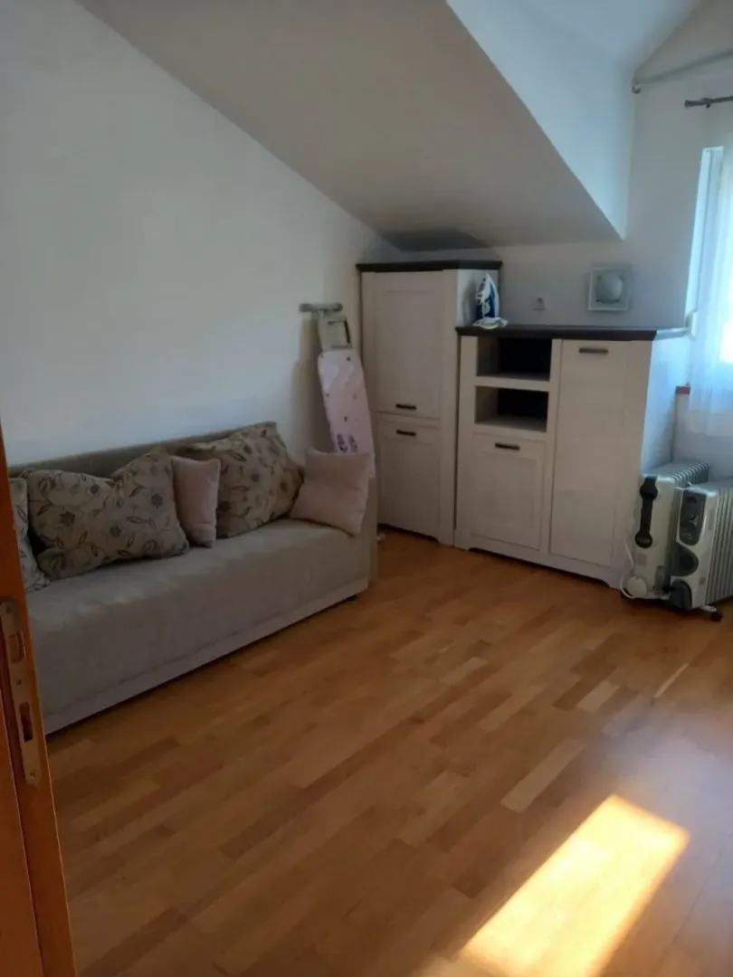 Dnevna soba sa kaučem, ormarima i drvenim podom.
