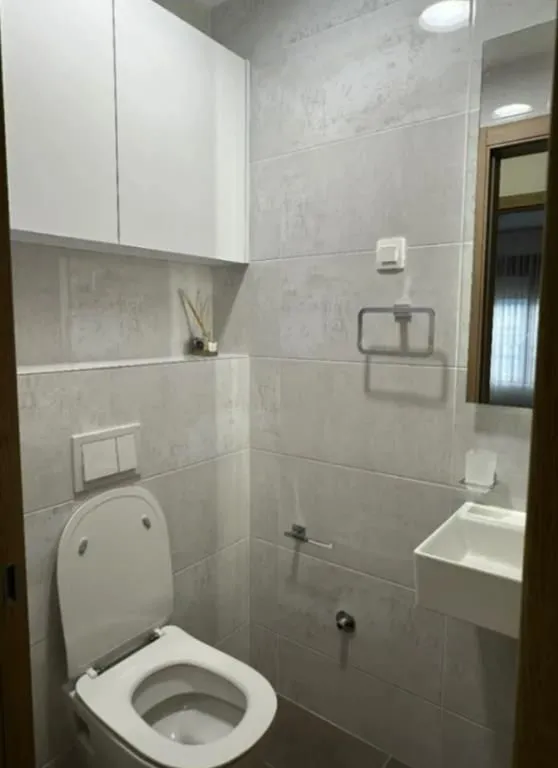 Smaller bathroom with a toilet, washbasin, mirror and wall cabinet.
