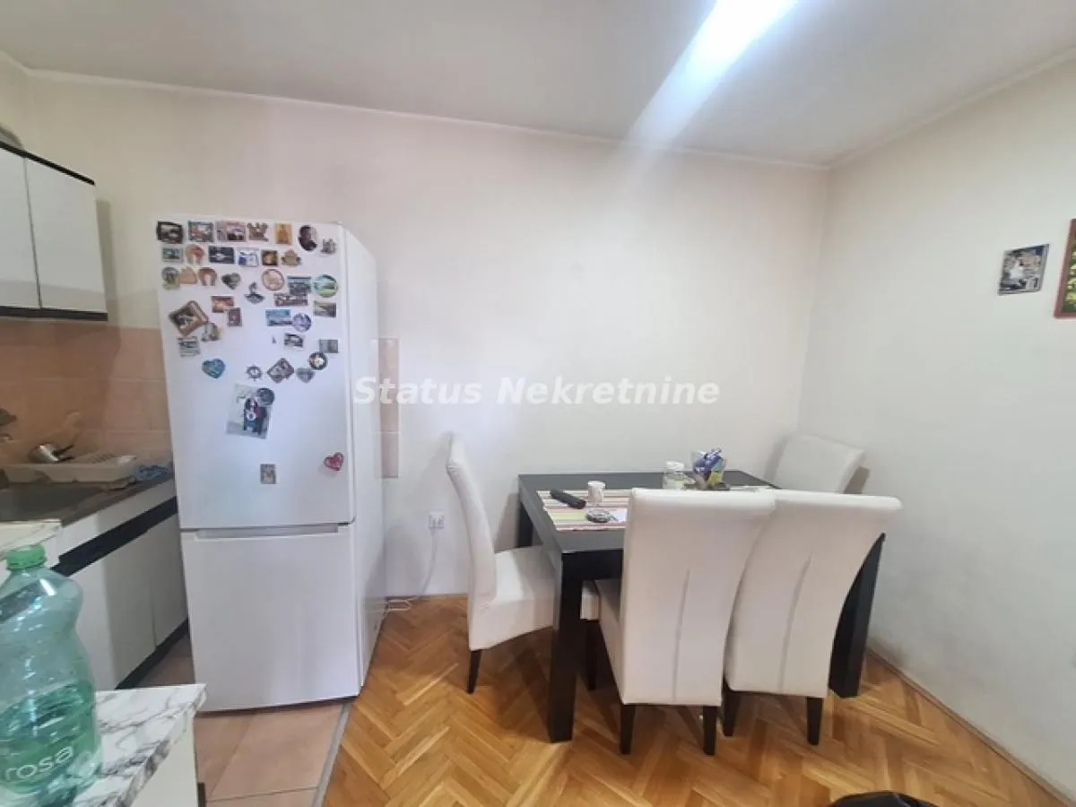Kuhinja sa trpezarijskim stolom i belim stolicama.