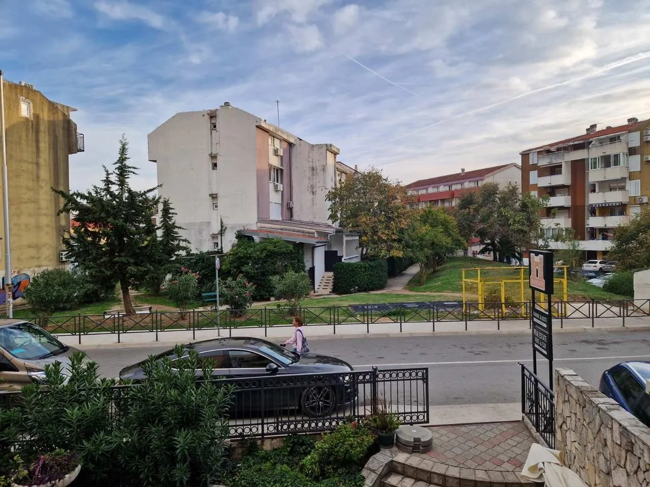 Pogled sa terase na ulicu i okolne zgrade sa zelenilom.