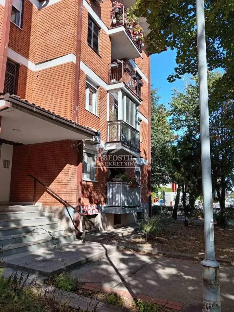 Spoljašnji izgled stambene zgrade sa ciglom i balkonima.