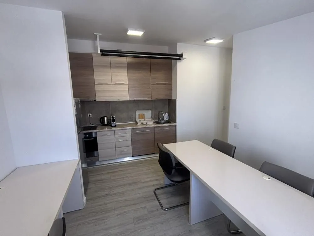 Kitchen equipped with wooden cabinets and appliances, connected with office desks.