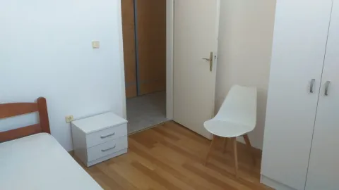 Jednostavna spavaća soba sa bijelim namještajem i drvenim podom. - image 4