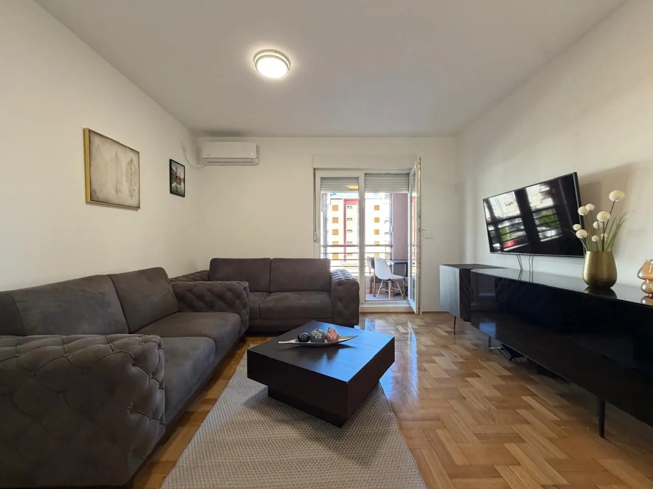 Living room with sofa, coffee table, TV and access to the terrace.