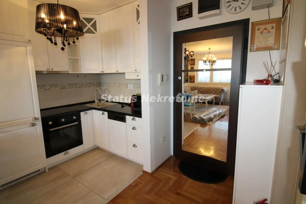 View of a white kitchen with built-in appliances and a door leading to the living room.