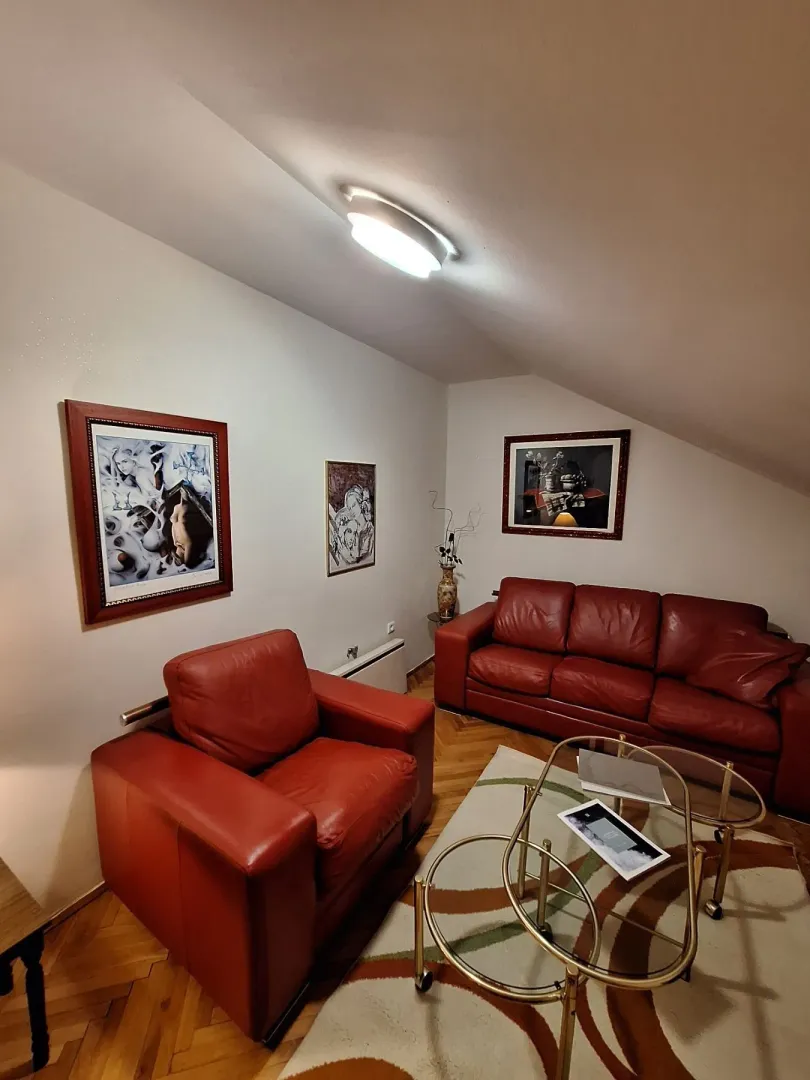 Living room featuring red leather furniture and artwork on the walls.