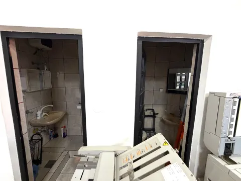 View of two bathrooms from a hallway with office equipment. - image 13