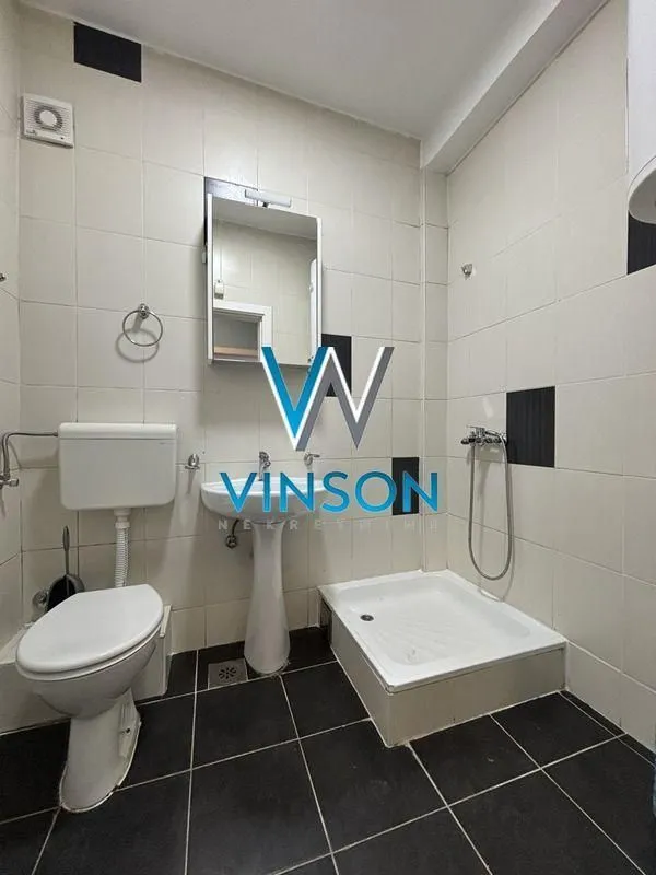 Small bathroom with a shower cabin, washbasin, and toilet.