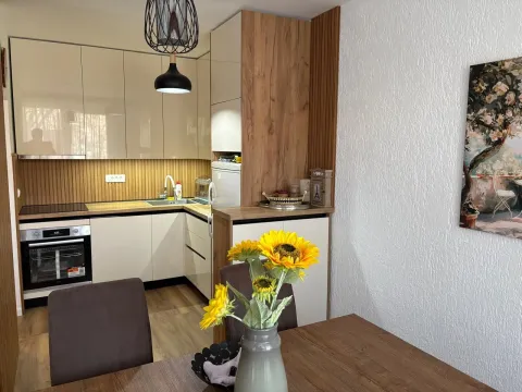 Kitchen with beige and wooden cabinets and a dining table. - image 5
