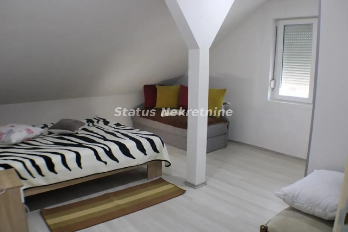Attic space furnished with beds and white sloping walls.