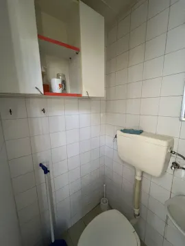 A simple toilet with white tiles and a wall cabinet. - image 4