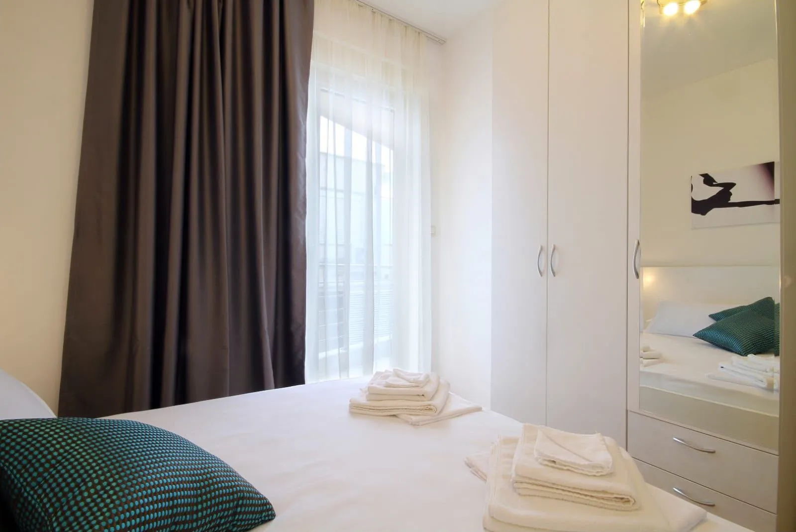 Furnished bedroom with a double bed, wardrobe, and light curtains.