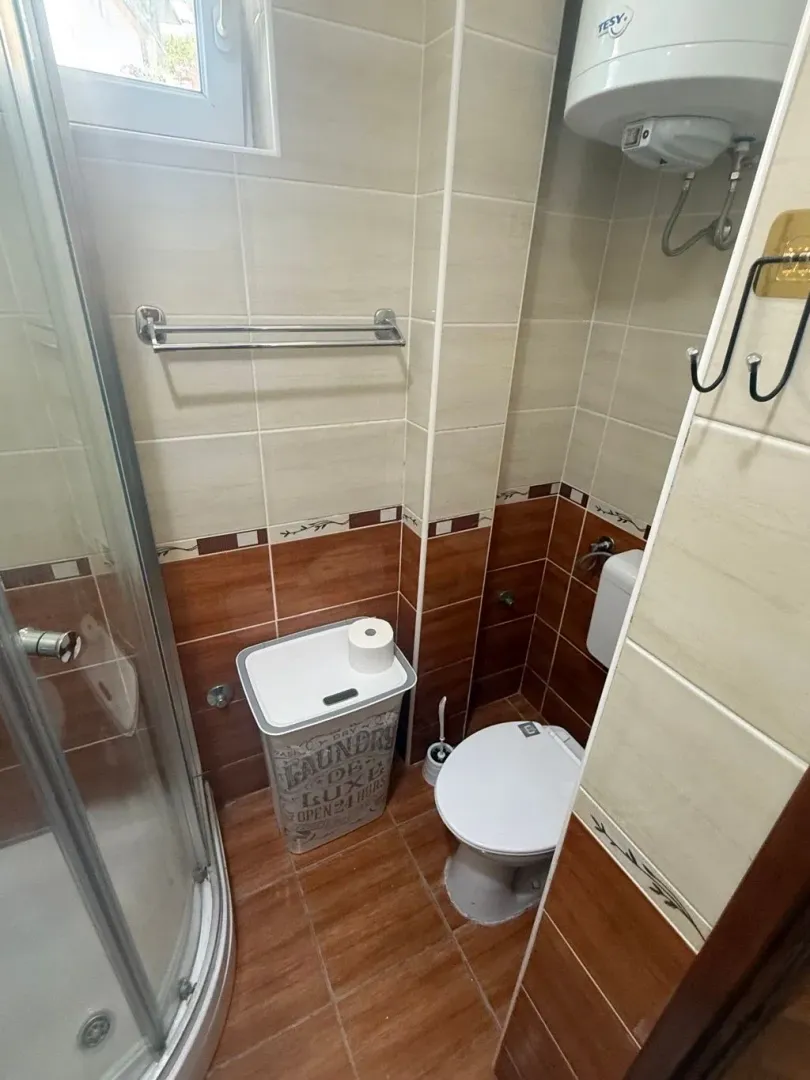 Manje kupatilo sa tuš kabinom, WC šoljom i bojlerom.