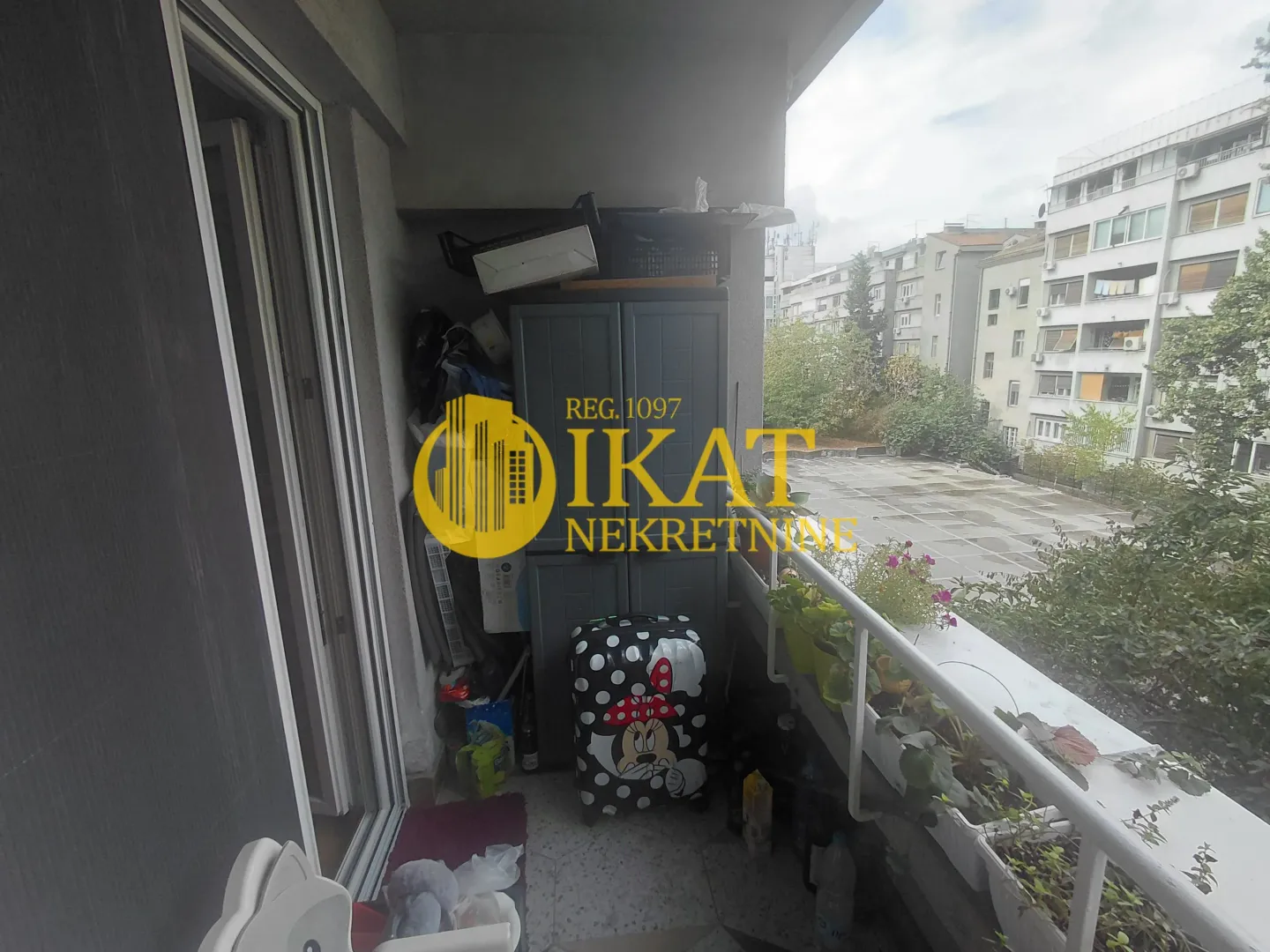 Nenamešten balkon sa pogledom na susedne zgrade.