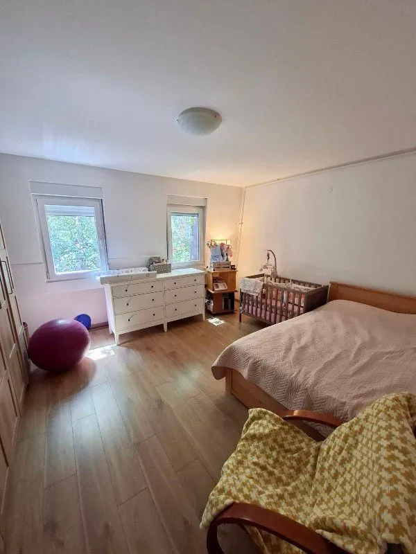 Bedroom with a double bed, baby crib, and chest of drawers.