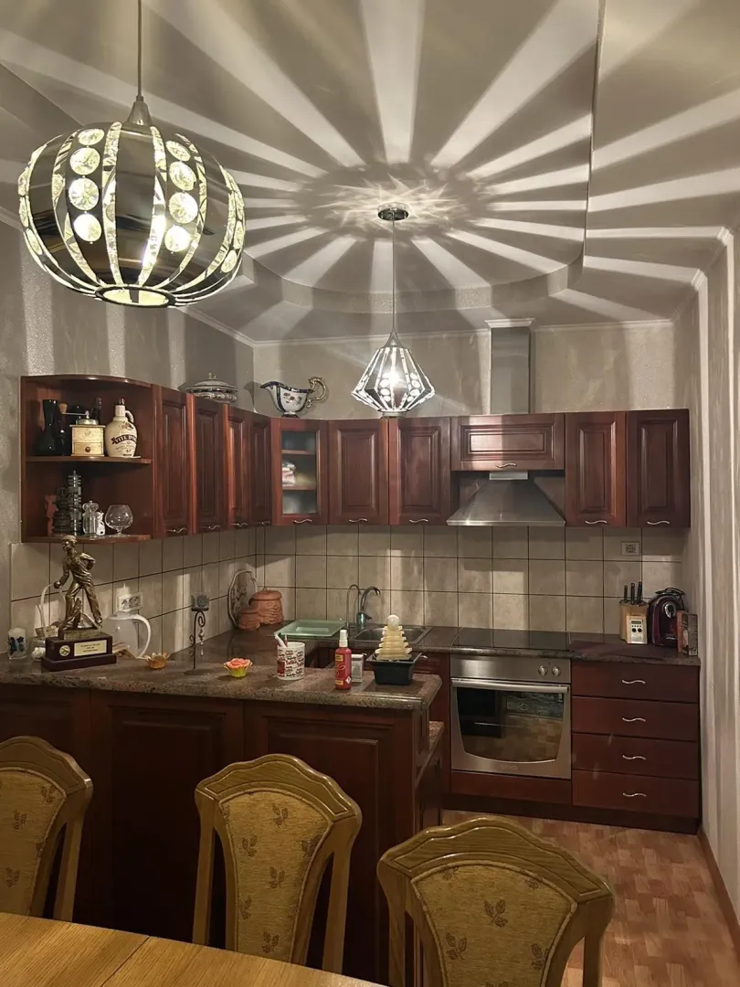 A kitchen with wooden cabinetry and decorative lighting.