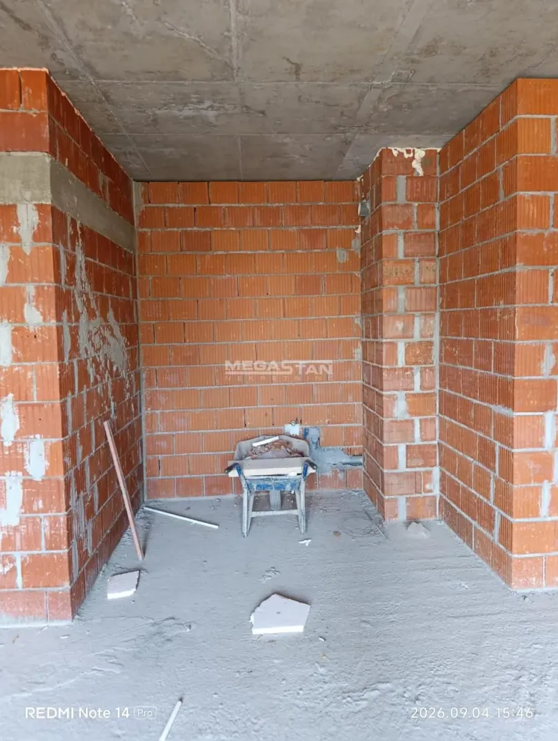 Prazna prostorija u izgradnji sa ciglenim zidovima i betonskim podom.