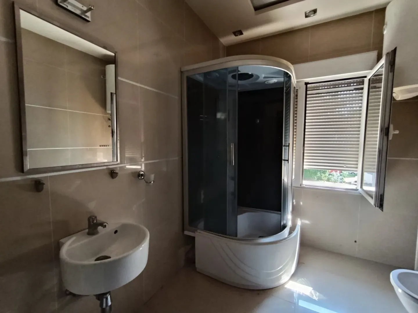 Bathroom equipped with a sink, shower cabin, and mirror.