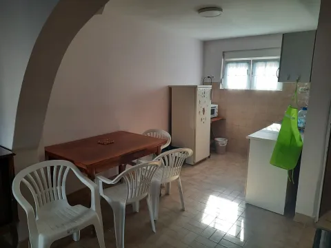 Smaller kitchen with a dining table and white plastic chairs. - image 2