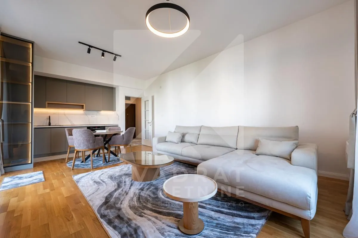Living room with a sofa, coffee tables, and a view of the kitchen in the background.
