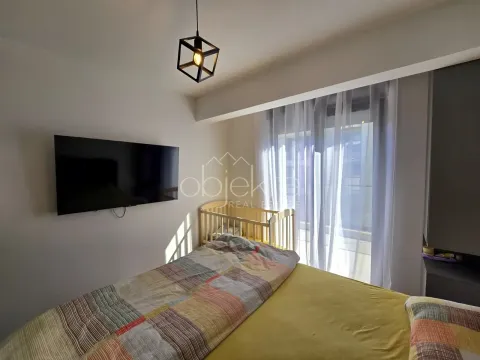 Spavaća soba sa krevetom, televizorom na zidu i izlazom na terasu. - image 10