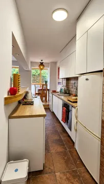 Long kitchen with white cabinets and a dining area in the background. - image 7