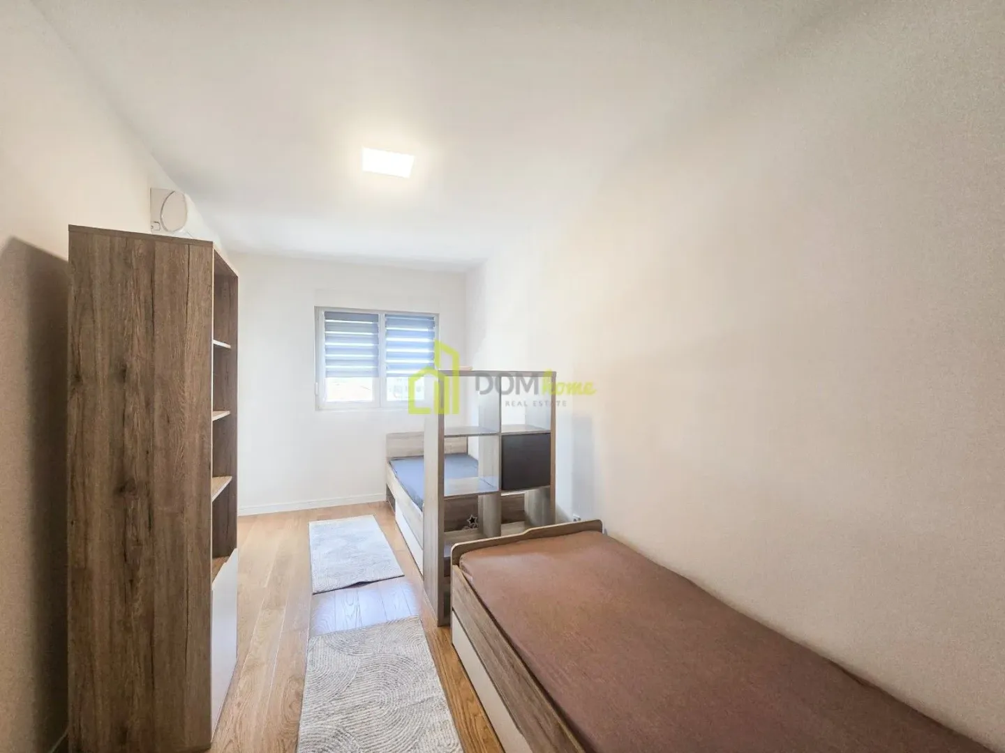 Children's bedroom with two beds, wardrobe and a window.