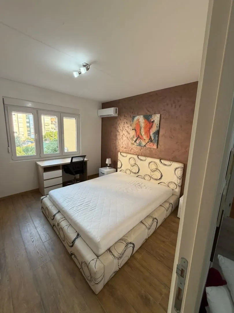 Furnished bedroom with a double bed, desk, and a window.