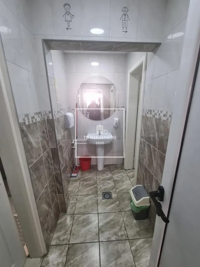 View of a restroom area with a sink and tiling.