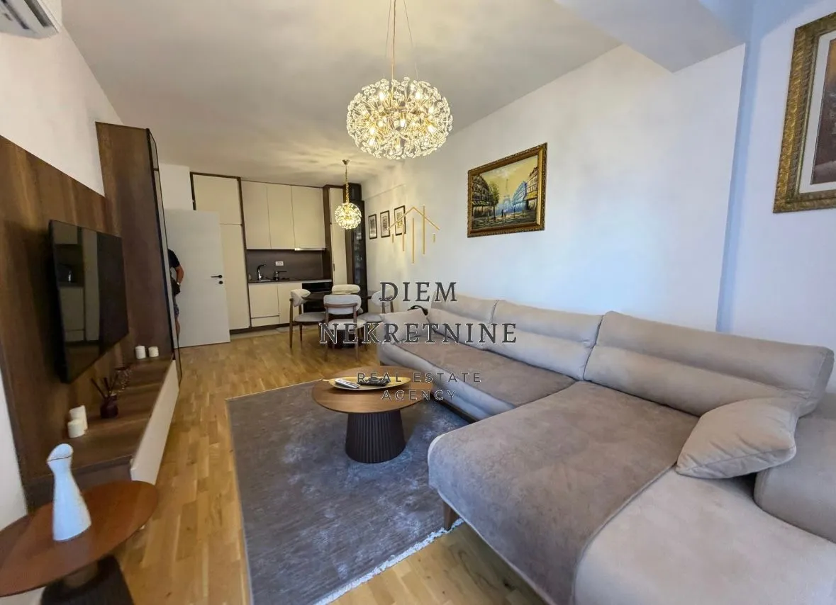 Spacious living room with a sofa and a dining area in the background.