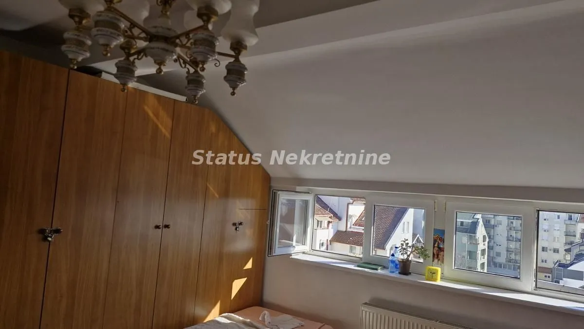 Potkrovlje sa drvenim plakarom, krevetom i prozorima.