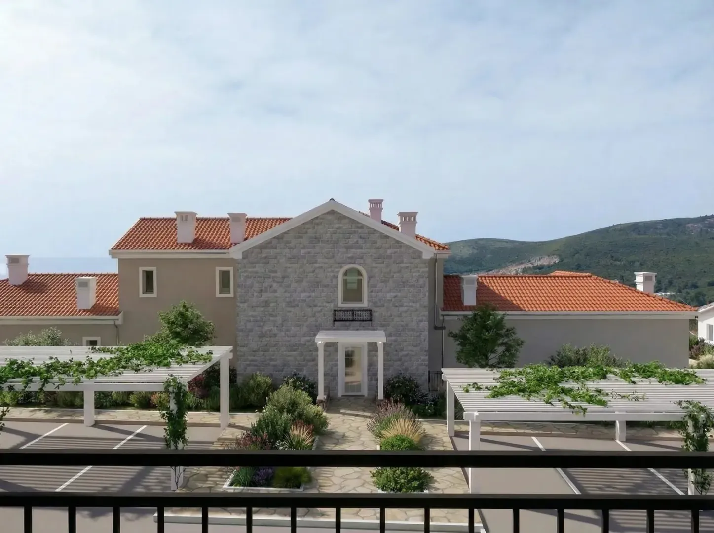 Pogled sa terase na dvorište i fasadu kuće sa kamenim detaljima.