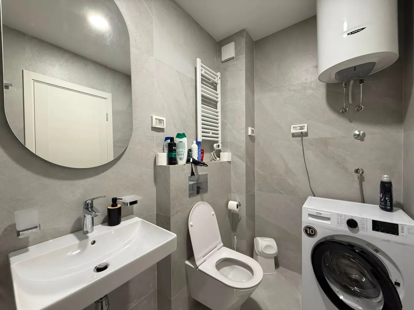 Moderne kupatilo sa umivaonikom, WC šoljom, tuš kabinom i mašinom za veš.