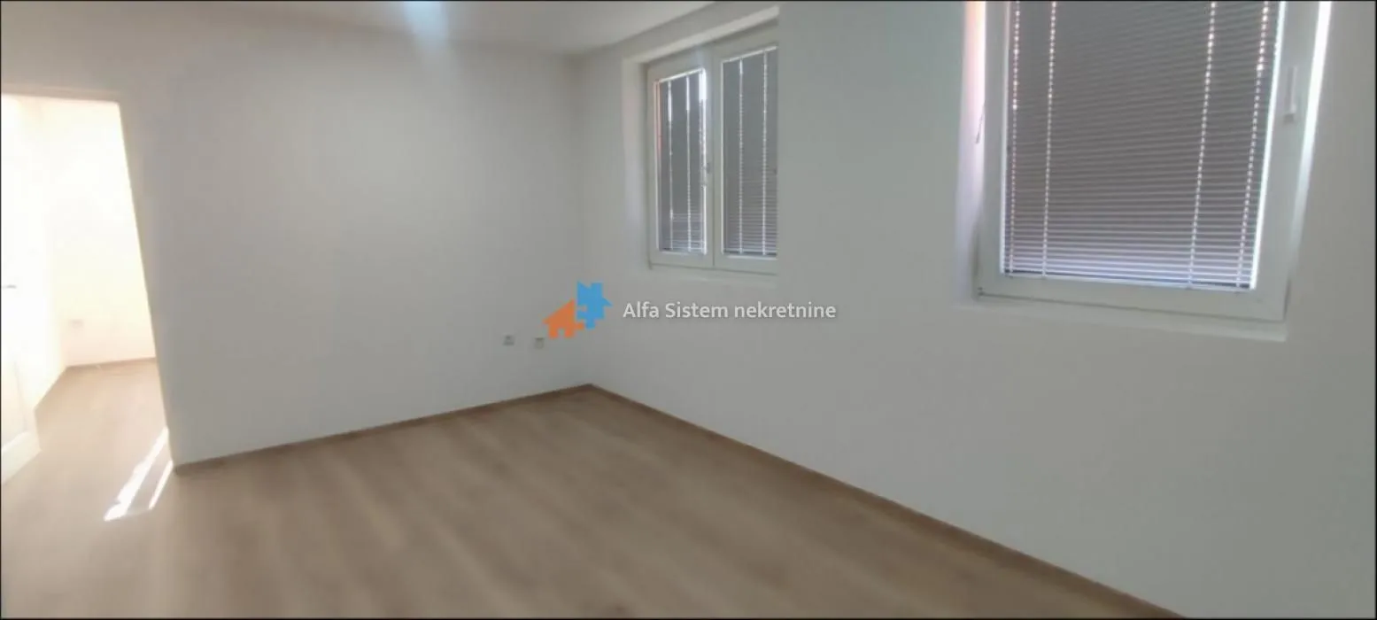 Empty unfurnished room with white walls and two windows.
