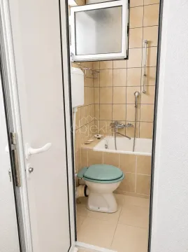 Manje kupatilo sa kadom i wc šoljom, obloženo keramičkim pločicama u bež tonovima. - image 6