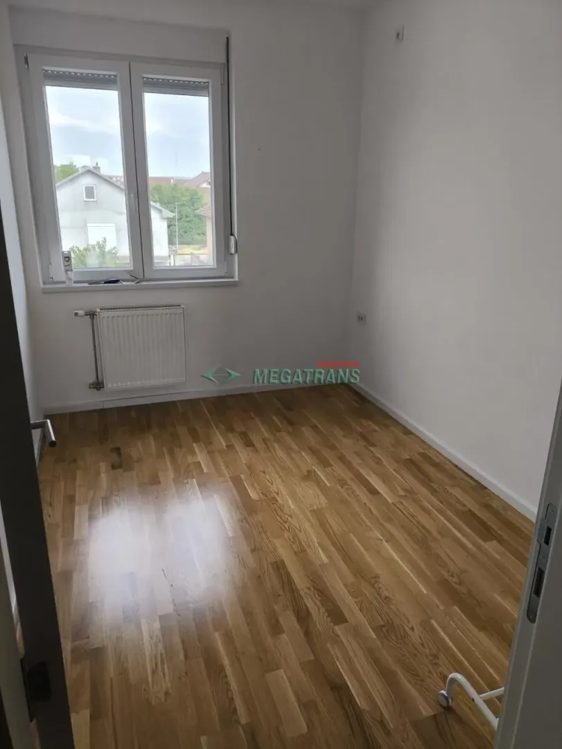 Prazna soba sa parketom i prozorom.