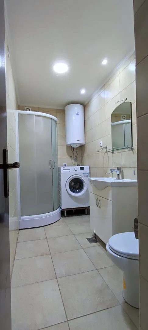 Bright bathroom with a shower cabin, washing machine, and water heater.